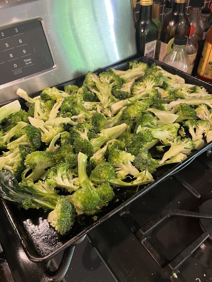 Broccoli florets spread on a sheet pan before roasting with meatloaf