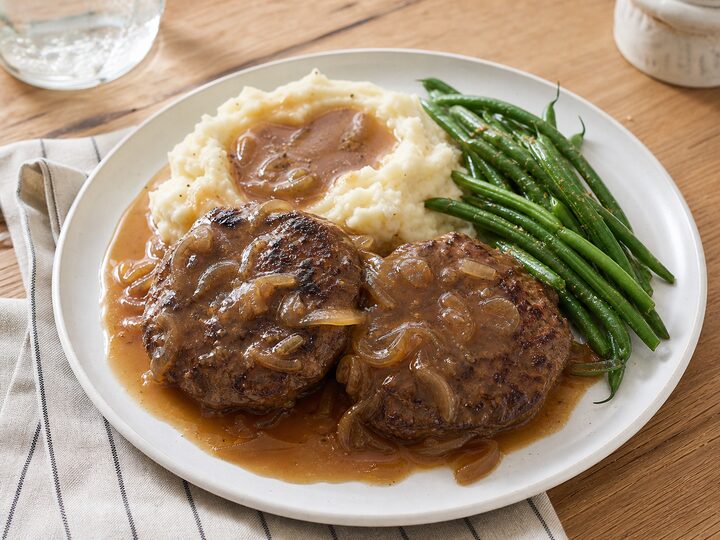 Salisbury steak patties with onion gravy, mashed potatoes, and green beans